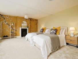 A bedroom with two single beds beside a wooden nightstand with a lamp and a decorated wall at Holmer House Farm in Holmer near Hereford