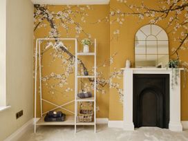 A room with yellow floral wallpaper a white shelf with towels and a fireplace with a mirror at Holmer House Farm in Holmer near Hereford
