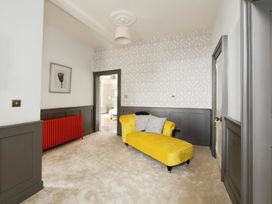 A room with a yellow chaise lounge sofa a red radiator patterned wallpaper and a doorway at Holmer House Farm in Holmer near Hereford
