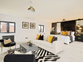 A bedroom with a bed, a white sofa with yellow and black pillows, black chairs, a gray coffee table, and black and white rug at Holmer House Farm in Holmer near Hereford