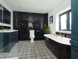 A bathroom with a bathtub toilet vanity with sink and black tiled wall at Holmer House Farm Holmer near Hereford