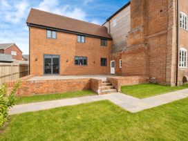 A backyard with a brick patio and steps leading to a grass lawn at Holmer House Farm in Holmer near Hereford