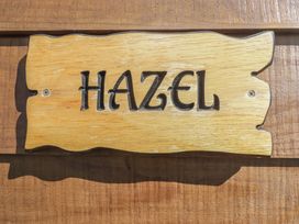 A wooden sign with the word Hazel carved on it attached to a wooden surface at The Hazel Pod in Cowbridge