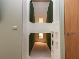 A room with white bunk beds and green wall panels with a wooden door on the right