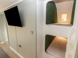 A room with bunk beds built into the wall and a wall mounted television at The Hazel Pod in Cowbridge