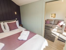 A bedroom with a bed with pillows and towels and a living room with a sofa and pillows at The Hazel Pod in Cowbridge