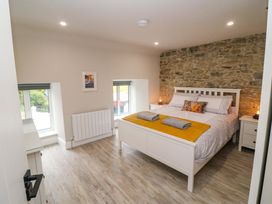 A bedroom with a bed, nightstands, and windows at Valley View House in Kealkill, County Cork