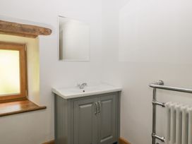 A bathroom with a sink, mirror, and radiator at Howgill Head in Kendal