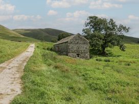 A stone building near a pathway surrounded by grass at Howgill Head in Kendal