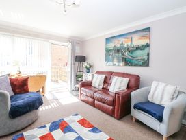 A living room with a red leather sofa a gray armchair and a colorful rug at 98 Waterside Park in Corton