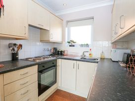 A kitchen with light wood cabinets black countertops a stove oven kettle dish rack and a window at 98 Waterside Park in Corton