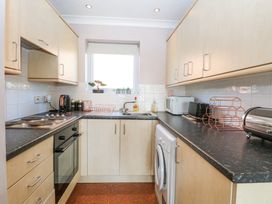 A kitchen with light wood cabinets black countertops a stove oven washing machine microwave and window at 98 Waterside Park in Corton