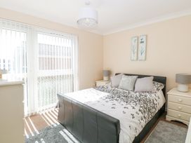 A bedroom with a bed between two bedside tables with lamps and sliding glass doors at 98 Waterside Park in Corton