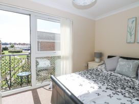 A bedroom with a bed a bedside table and a lamp next to a window with vertical blinds at 98 Waterside Park in Corton