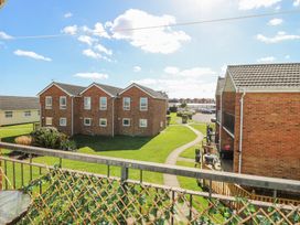 A view of brick residential buildings with a paved pathway and green lawn at 98 Waterside Park in Corton