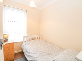 A small bedroom with a single bed next to a wooden drawer and window with vertical blinds at 98 Waterside Park Corton