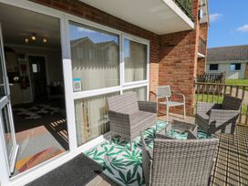 A balcony with wicker chairs and a small table and a chair on a patterned rug at 98 Waterside Park Corton