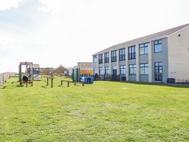 A playground with climbing and obstacle equipment on grass next to a two story building at 98 Waterside Park in Corton