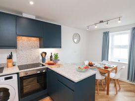 A kitchen with a stove, washing machine, table, and chairs at Belle's View in Scarborough