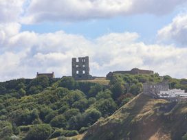 Castle ruins on a hill with trees and buildings at Belle's View in Scarborough