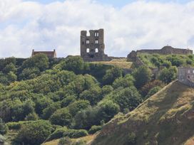 Castle ruins on a hill surrounded by trees at Belle's View in Scarborough