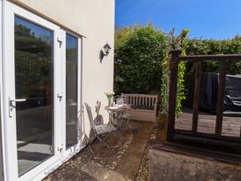 An outdoor patio with a table and chairs and a bench at Rosemarie Annexe in Axminster