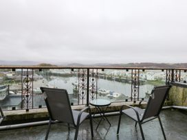 A balcony with chairs and a table overlooking a marina at Captain’s Quarters in Porthmadog