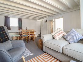 A living room with armchair sofa dining table and staircase at Glan Y Mor Borth in Borth