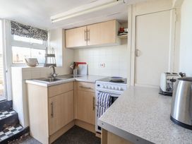 A kitchen with wooden cabinets a sink a stove toaster and kettle at Glan Y Mor Borth in Borth