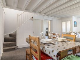 A dining area with a table set with plates wine glasses and a bottle of prosecco next to a carpeted staircase at Glan Y Mor Borth in Borth