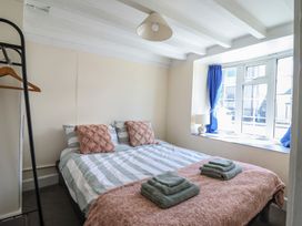 A bedroom with a bed striped bedding and folded towels near a window with blue curtains at Glan Y Mor Borth in Borth