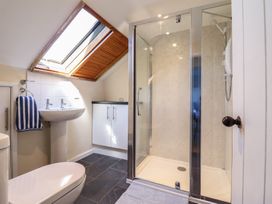 A bathroom with a shower cubicle pedestal sink toilet towel and skylight window at Glan Y Mor Borth in Borth