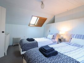 A bedroom with two single beds with folded towels on them and a lamp on a bedside table at Glan Y Mor Borth in Borth