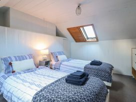 A bedroom with two single beds two bedside tables a lamp and a skylight window at Glan Y Mor Borth in Borth