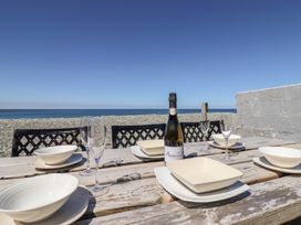 A picnic table set with plates bowls champagne glasses and a bottle of prosecco by the beach at Glan Y Mor Borth in Borth