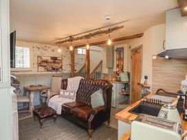 A living room with a sofa and kitchenette at Driftwood in Flamborough