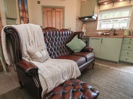 A living room with a sofa and kitchen area at Driftwood in Flamborough