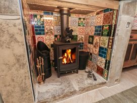 A fireplace with a wood stove and decorative tiles at Driftwood in Flamborough