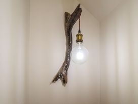 A light fixture with a bulb attached to a wooden branch at Driftwood in Flamborough