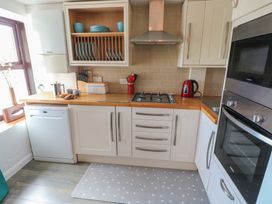 A kitchen with cabinets, a gas hob, a kettle, and a sink at Puffin Nook in Broad Haven