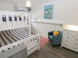 A bedroom with a bunk bed and armchair at Puffin Nook in Broad Haven
