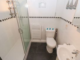 A bathroom with a shower, toilet, radiator, and sink at Puffin Nook in Broad Haven
