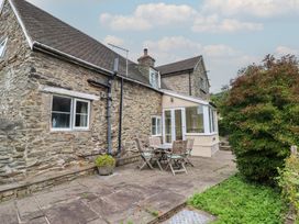 A garden with a stone house and wooden table and chairs at Hafod in Llangollen