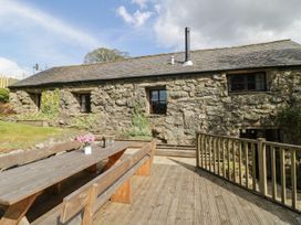 An outdoor seating area with a stone house and wooden table at Cyffdy Cottage - Arenig Bala