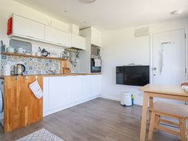 A kitchen with white cabinets wooden countertops patterned tile backsplash and a wall mounted tv at Meadows Edge Perranwell near Goonhavern