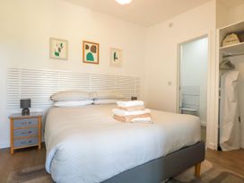 A bedroom with a double bed and folded towels a bedside table with a lamp and an open door leading to a bathroom at Meadows Edge in Perranwell near Goonhavern