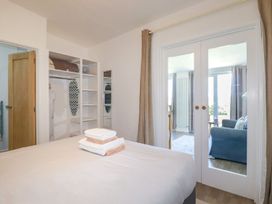 A bedroom with a bed and folded towels on it an open closet with an ironing board and a mirrored door leading to a living room at Meadows Edge in Perranwell near Goonhavern