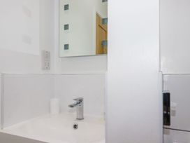 A bathroom sink with a faucet a cup and a mirror at Meadows Edge in Perranwell near Goonhavern