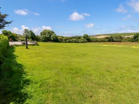 A large grassy field with picnic benches and trees under a blue sky at Meadows Edge in Perranwell near Goonhavern