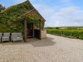 An outdoor seating area with wicker chairs and a table next to a door covered with ivy at Babes Cottage in Perranwell near Goonhavern